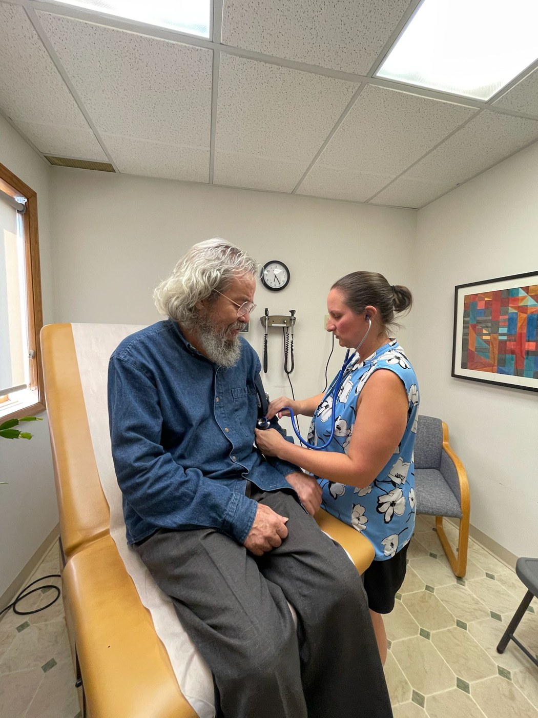 A nurse listening to a patient's heart at the center